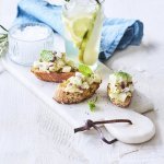 Bruschetta met perensalsa en blauwe schimmelkaas liggen op een marmer schaaltje samen met een homemade rozemarijnlimonade met peer. 