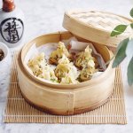 Er staat een stoommandje op het marmere aanrecht waarin verschillende dumplings liggen. Er staat bovenaan een dipsausje op basis van sojasaus en een chinees kannetje. 