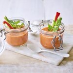 Twee bokaaltjes met gazpacho staan op een marmer plankje, een ideaal alternatief voor te weinig glazen. We gaven de gazpacho een feestlook met staafjes komkommer en paparika in het bokaaltje te laten op springen.  