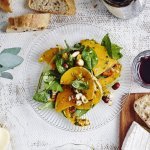 Een glazen bordje staat op tafel met geroosterde partjes pompoen. De salade krijgt een mooi groen kleurtje door de verse spinazie, hij is afgewerkt met enkele hazelnoten. Op en top een herfstsalade boordevol smaak.