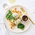 Knoedels, gemaakt van brooddeeg, liggen bovenop gestoofde blokjes peterseliewortel en zoete aardappel. Deze vegetarische ballen worden opgediend met een sausje van bospaddenstoelen. Het sausje staat mee op het bord in een potje. Goud bestek en kerststerren liggen langs het bord.