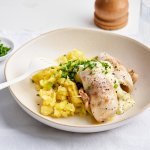 Op het aanrecht staat een portie eten klaar. Een schep preipuree met hierop twee visrolletjes van de zeebaars, afgewerkt met een koud sausje op basis van yoghurt. 