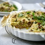 Een heerlijke quiche vers gebakken in een witte porseleinen taartvorm. Hij is gemaakt met spruitjes, champignons en prei. We voegden nog wat walnoten toe voor een extra bite. 