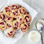 Rolletjes gemaakt van beslag met yoghurt, gevuld met framboosje. De rolletjes liggen tegen elkaar in een cirkelvorm. Heerlijke kleuren om naar te kijken en nog beter om op te eten.