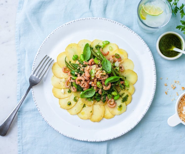 Aardappelcarpaccio met groene sla en verse garnalen. Fijn gesneden aardappel schijfjes met groene sla en verse garnalen.