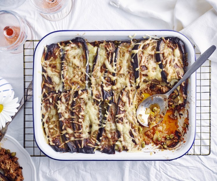 Een grote ovenschotel met aardappellasagne staat op tafel. Er is al een portie uitgedeeld, maar er zijn er nog 5 te verdelen. Perfect te combineren met een glaasje rosé. 