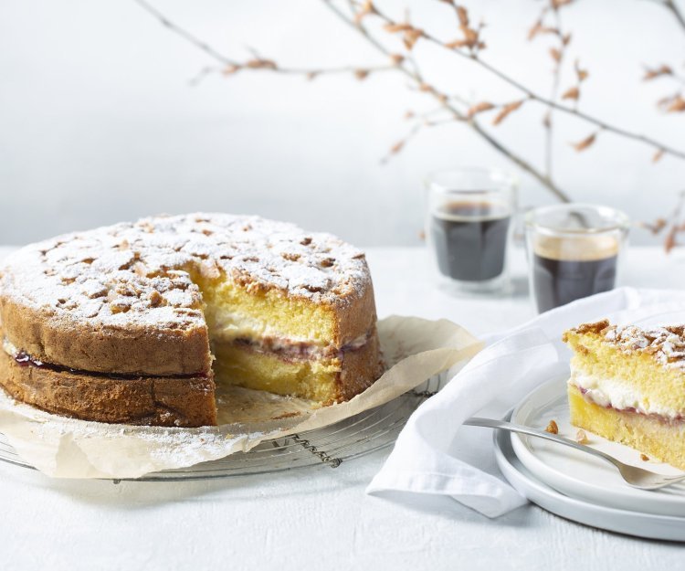 Biscuit met vanillepudding en slagroom Een biscuit met vanillepudding en slagroom staat op tafel op een taartrooster. Er is al een stukje aangesneden om de lijnen duidelijk te laten zien van de pudding en slagroom. Koffie uitgeschonken, vorkje prikken en aanvallen die taart.