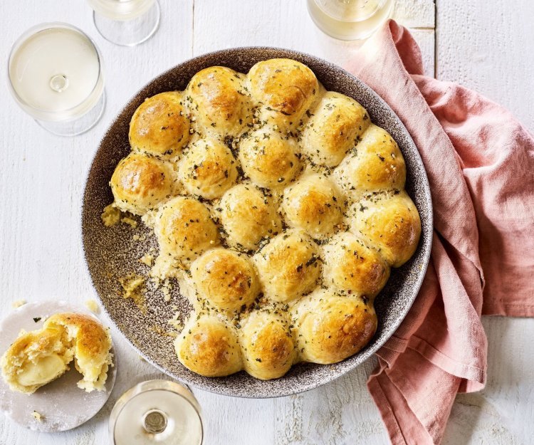 In het midden van de tafel vind je een groot rond keramiek bord in aardekleur. Hierin liggen de goudgele briochebroodjes met knoflookboter, en gevuld zijn met abdijkaas. Instant feestlook en heerlijk smaakvol als bijgerecht.  