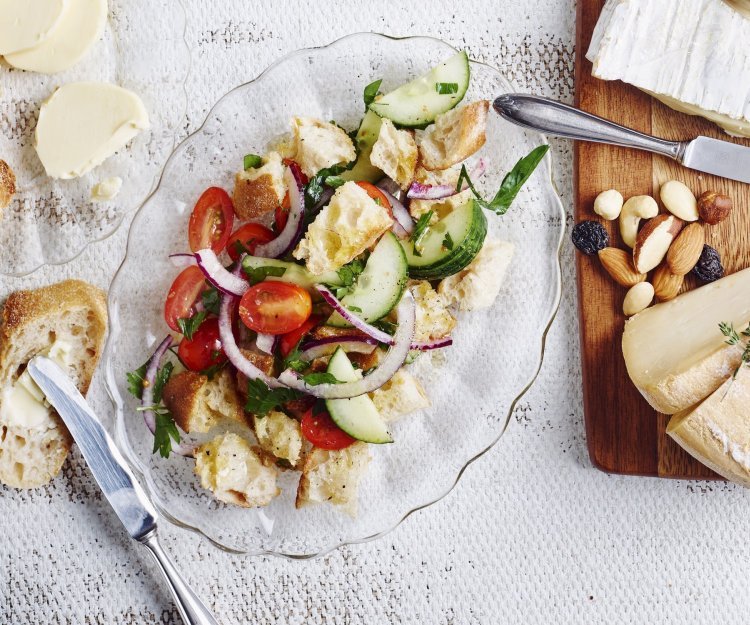 Broodsalade met tomaat en komkommer Een glazen schaaltje, ovaalvormig, gevuld met knapperige croutons, tomatenstukjes en komkommermaantjes.