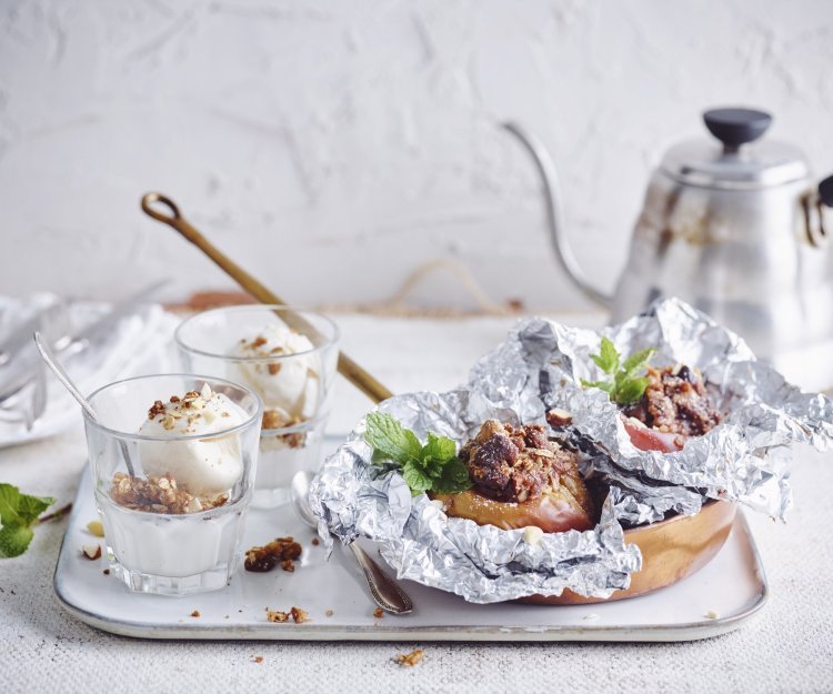 Een vers gepofte appel vanop de bbq ligt in een klein pannetje op een dienblad vergezeld met een glaasje vanilleijs en verse koffie.