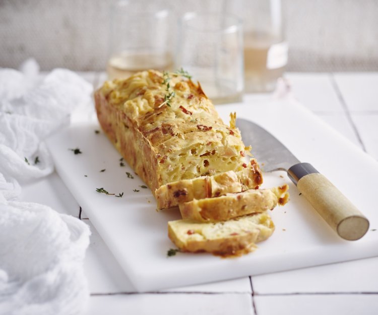 Een cake die niet zoet is, maar hartig. Wij maakte hem met appel, kazen van bij ons en spekjes... heerlijk! Hij ligt aangesneden op een witte snijplank en werd afgewerkt met verse tijmblaadjes. 