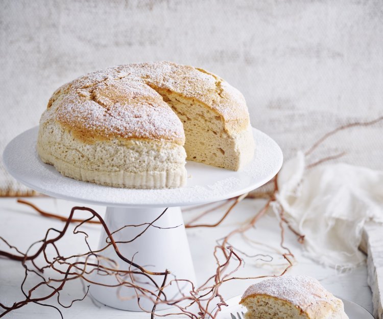 Een Japanse cheesecake, ook wel cheescakesoufflé genoemd, staat op een taartstandaard. Er is al 1 stukje aangesneden om meteen te smullen. 