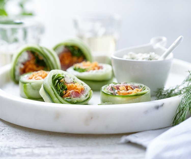 Komkommerrolletjes met cottage cheese en rosbief Rolletjes van komkommer gevuld met cottage cheese, wortel, rucola en rosbief. Een heerlijke gezonde en kleurrijke snack op een bordje van marmer. De overige mengeling met de cheese is geserveerd in een dippotje om eventueel een extra toefje te nemen.