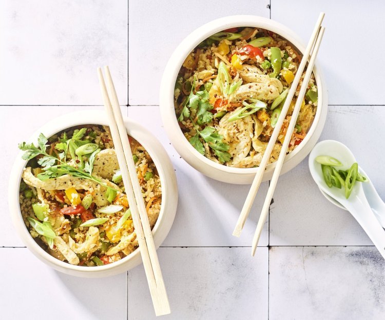 Twee kommetjes staan op het aanrecht. Wij maakten een op-en-top Belgische variant op de Nasi goreng, nl eentje met bloemkoolrijst, paprika, erwtjes en kip van bij ons. 