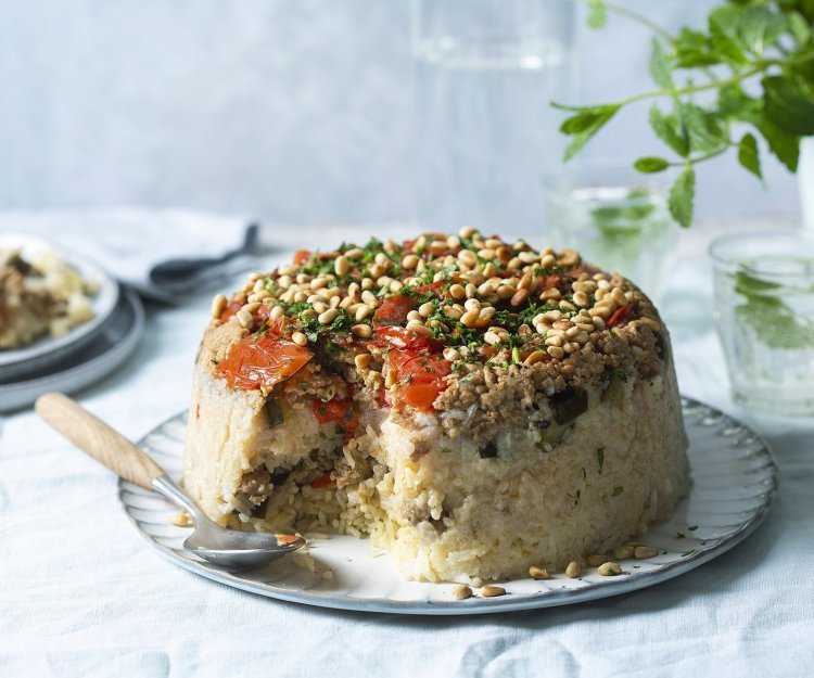 Omgekeerde rijstschotel met groenten en kip Een Libanese rijstschotel die omgekeerd gepresenteerd wordt op een groot bord. Wij voegde verschillende groenten en gehakt toe om een volledig maal klaar te hebben.