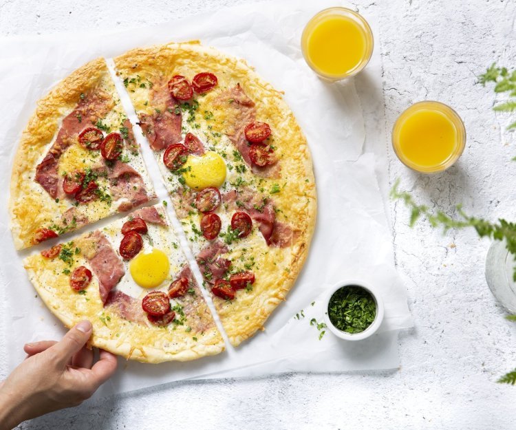 Ontbijt plaattaart met ei, kaas, ham en kerstomaat Een taartje als ontbijt? Yes, we can! Dit is er eentje van bladerdeeg met ei, kaas, ham en kerstomaat. HIj ligt aangesneden in 4 op tafel samen met 2 glaasjes versgeperst fruitsap. Een hand neemt gaat meteen ten aanval om dit heerlijk ontbijt niet koud te laten worden.