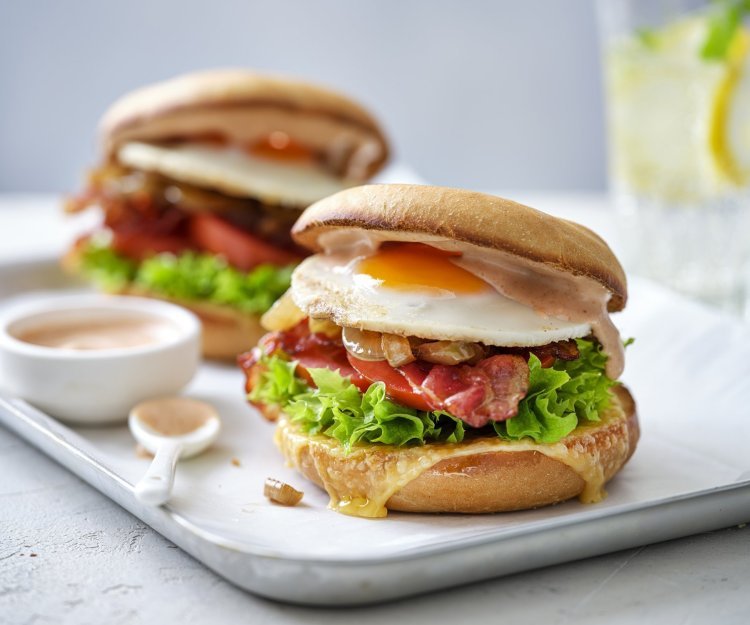 Een burger als ontbijt, dat is er eentje met een spiegelei, spek en groentjes. Er liggen twee stuks op een schaaltje met het sausje erbij geserveerd in een potje, klaar om te proeven. 