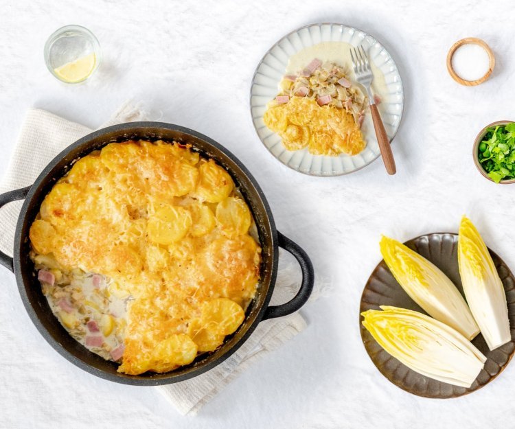 Ovenschotel met witloof, hesp, kaassaus en aardappelen Heerlijke gratin met witloof, hesp, aardappel en veel kaas! De ovenschotel is klaargemaakt in een ronde zwarte ovenschotel, hieruit is al 1 portie uitgeschept.