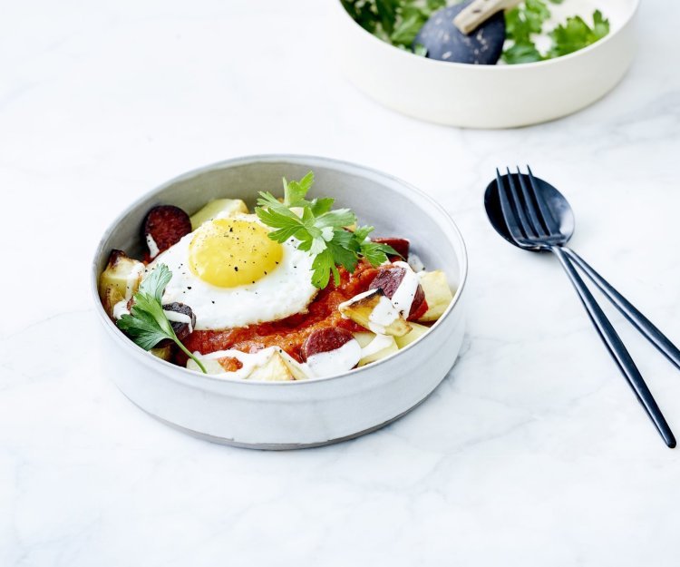 Patatas bravas opgediend in een diep bordje met tomatensaus, spiegelei, verse sla en yoghurtdressing. Ik wil er meteen aan beginnen! 