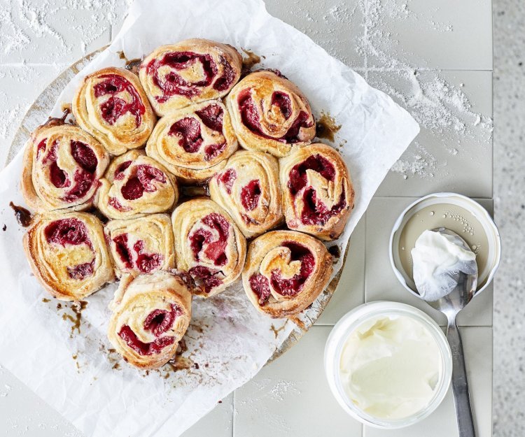 Rolletjes gemaakt van beslag met yoghurt, gevuld met framboosje. De rolletjes liggen tegen elkaar in een cirkelvorm. Heerlijke kleuren om naar te kijken en nog beter om op te eten.