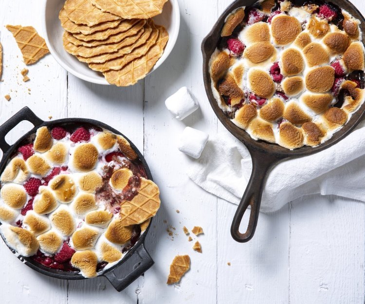 S’mores dip met frambozen en rode besjes S'mores dip maak je met marshmallows die lichtjes in de oven gaan om te smelten en te kleuren. Wij voegden ook nog framboosjes en rode besje toe in onze gietijzeren zwarte pan. Een heerlijk dessert om te dippen met Jules Destrooper koekjes.