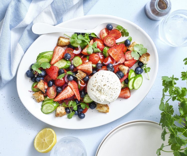 Salade met kerstomaten, aardbei en burrata Er staat een grote schaal op tafel boordevol zomerse toppers. Denk maar aan tomaatjes, aardbeien, bosbessen, komkommers en burrata. Dit geeft echt verfrissing tijdens een zwoele zomerdag. Er ligt een citroentje langs, een glas water en verse kroiander.