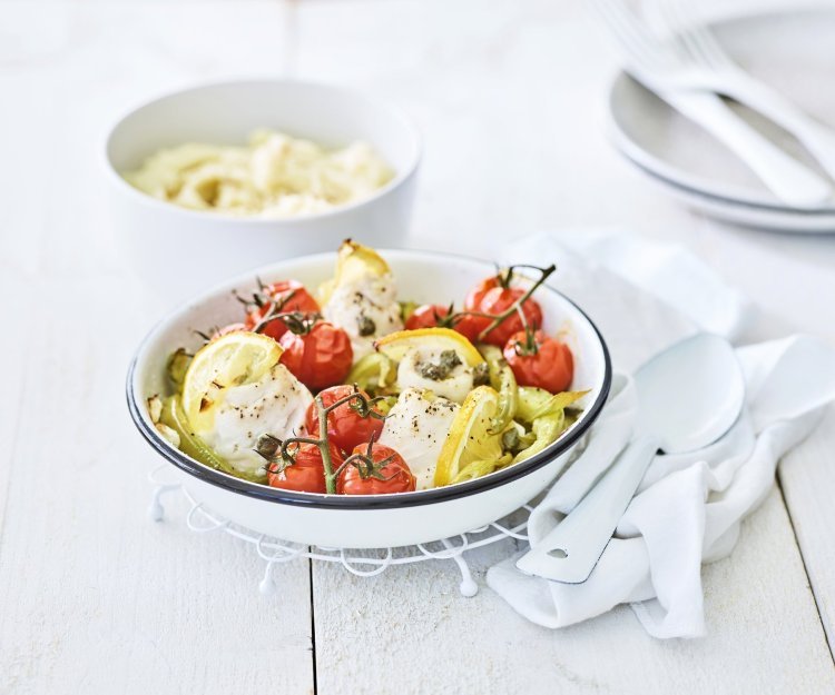 In een ronde ovenschaal liggen de tongrolletjes te blinken. De ovenschotel werd aangevuld met kerstomaatjes in trosvorm en stukjes groene paprika. Er werden ook partjes citroen toegevoegd voor een extra frisse smaak. In de achtergrond is een kommetje gevuld met puree.