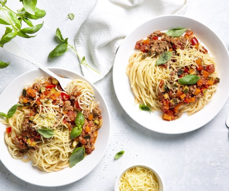 Twee borden gevuld met huisgemaakte spaghetti bolognaise. Afgewerkt met basilicumblaadjes die zorgen voor extra smaak en kleur in je bord. 