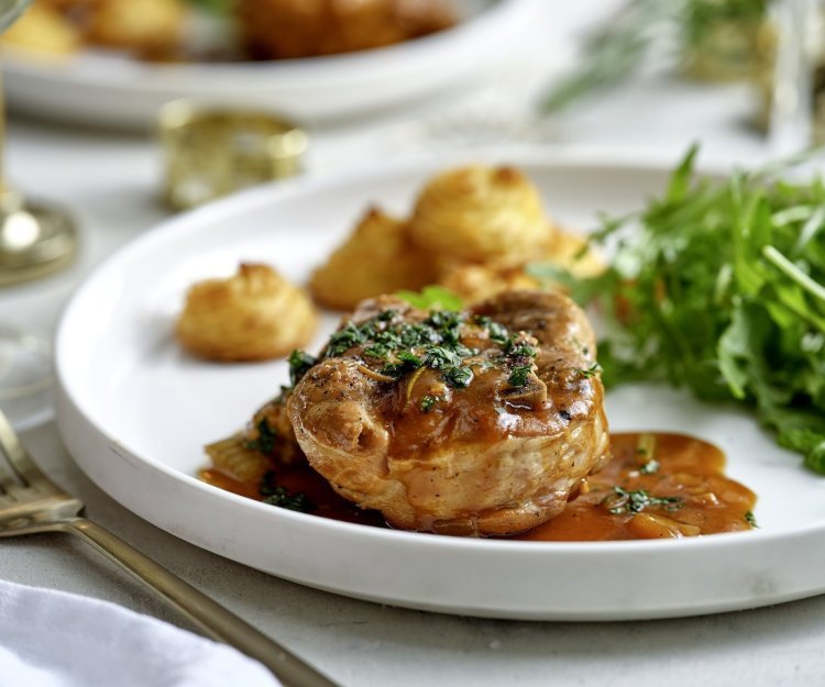 Stoofpotje met varkensvlees en pomme duchesse van pastinaakpuree Het hoofdgerecht is geserveerd op een wit groot bord. Ieder krijgt een portie schenkel, pommes duchesse en frisse rucolasla.