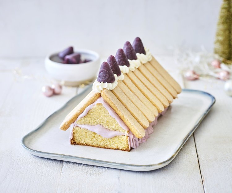 Taart kersthuisje met cuberdon Op een schaaltje staat een taart in de vorm van een kersthuisje gemaakt uit een cake met lange vingers en cuberdons. De cake is de vorm van het huis en hierop werden de lange vingers gelegd als dakplaten. De cuberdons staan in een toefje slagroom hier bovenop.
