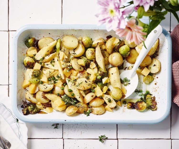 Een heerlijk geurende ovenschotel staat op het aanrecht. Het is een traybake van aardappelen met spruitjes, pastinaak en Beauvoordse brokkelkaas.