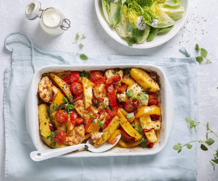 Traybake met aardappelwedges, groenten en kip Een heerlijke hoofdmaaltijd in één ovenschaal met stukjes aardappel, tomaten, paprika en kip. Er is ook een knapperige salade van little gem met yoghurtdressing.
