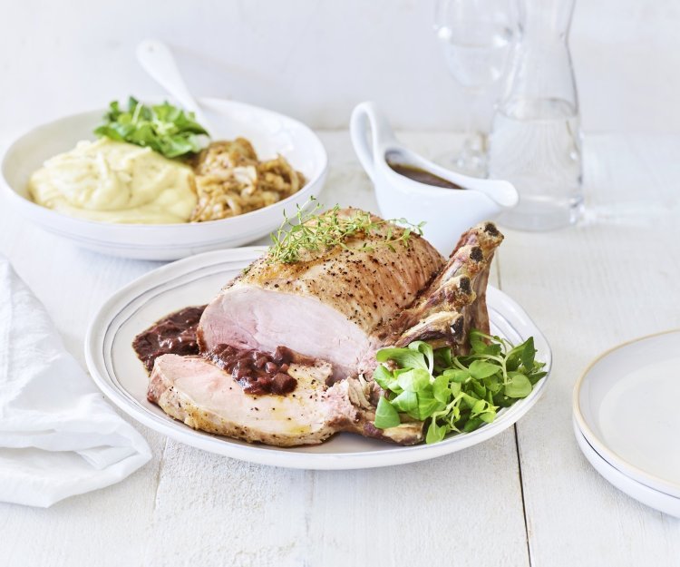 Varkenskroontje met puree, Pas de Rouge-kaas en witloof Een varkenskroontje ligt op een groot wit bord, aangesneden en opgediend met de rode wijn saus. In de achtergrond staat de aardappelpuree en de stukjes witloof. Het varkensvlees is mooi roos gebakken.