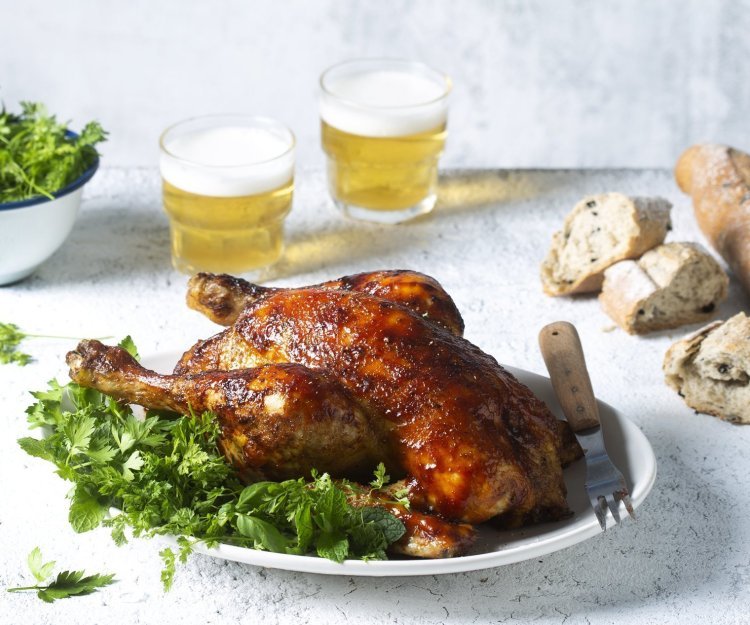 Volledige kip op de BBQ met een frisse kruidensalade Een volledige kip op de BBQ op een blikje bier klaargemaakt, dit noemen we canned chicken. Deze kip kreeg een kruidige jas aan door de BBQ-saus. Ze ligt op een kruidige salade klaar om te knippen in stukken en op te peuzelen.