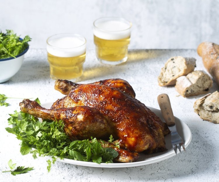 Een volledige kip op de BBQ op een blikje bier klaargemaakt, dit noemen we canned chicken. Deze kip kreeg een kruidige jas aan door de BBQ-saus. Ze ligt op een kruidige salade klaar om te knippen in stukken en op te peuzelen. 