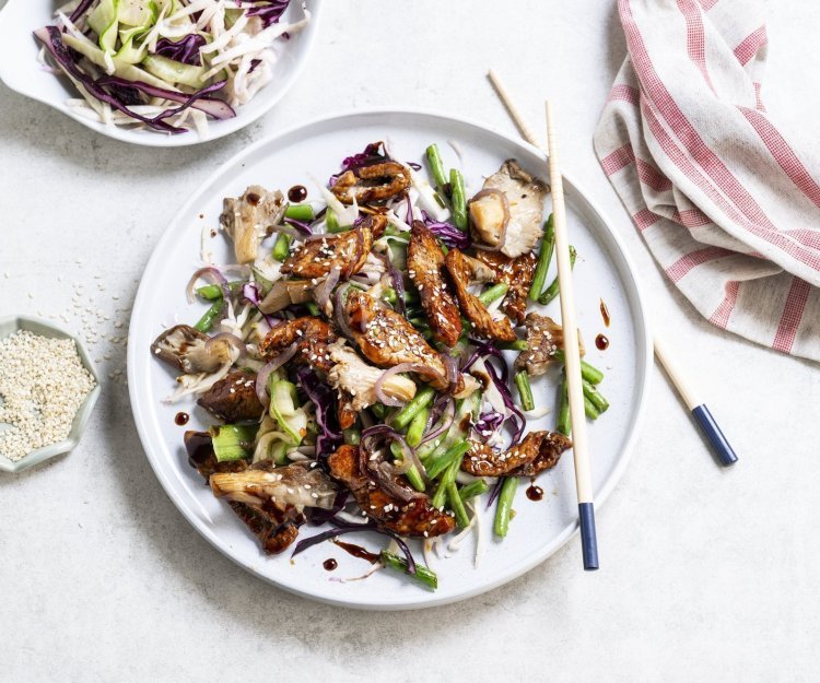 Wok van kalfsvlees, boontjes, kolen en oesterzwammen Op tafel staat een groot wit bord met hierop het gerechtje uitgeschept. Het vlees kreeg een mooi sticky kleurtje door de marinade. De boost aan groentjes is aanwezig in dit gerechtje.