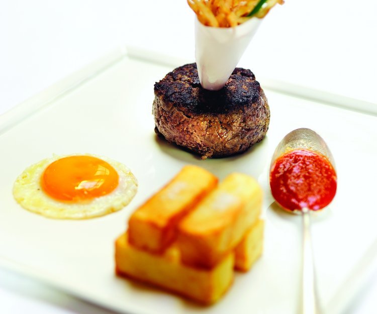 Burger de bœuf « Jockey Club » avec des pommes pont-neuf, un œuf sur le plat et du ketchup maison Burger de bœuf « Jockey Club » avec des pommes pont-neuf, un œuf sur le plat et du ketchup maison