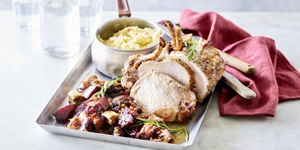 Gebraden varkenskroontje met rabarber, rode biet en dragon Het varkenskroontje ligt op een ovenplaat samen met de stukjes rabarber en rode biet. We serveren hem met een kommetje versgemaakte puree. Er ligt een donkerrode servette bij het gerecht om de rode biet nog meer te accentueren, een herfsttopper!
