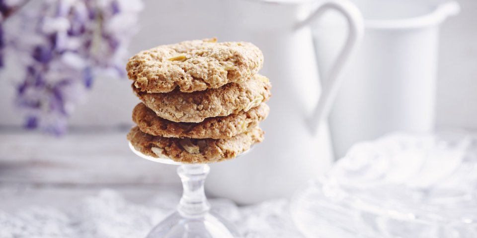 Koekjes met appel en pindakaas Heerlijke homemade cookies. Wij maakte er met appeltjes en pindakaas, een topcominatie. Ze liggen op de voet van een omgedraaid wijnglas. Achteraan de foto vind je een bloem van een Blauwe regen, melkkan en koffiekan.