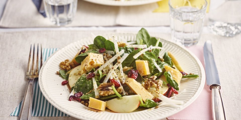 Maaltijdsalade met linzen, Flandrien Oud kaas, spinazie, koolrabi en appel Op tafel staan twee borden, mooi tegenover elkaar. De borden zijn gevuld met een slaatje van linzen, spinazie, reepjes koolrabi en appel en brokjes Flandrien kaas. Een kleurrijk en voedzaam gerechtje.