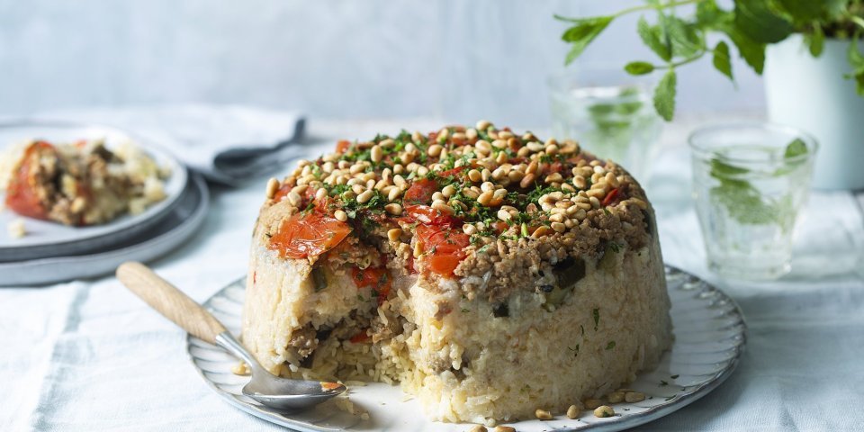 Omgekeerde rijstschotel met groenten en kip Een Libanese rijstschotel die omgekeerd gepresenteerd wordt op een groot bord. Wij voegde verschillende groenten en gehakt toe om een volledig maal klaar te hebben.