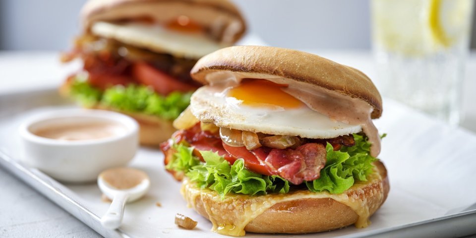 Een burger als ontbijt, dat is er eentje met een spiegelei, spek en groentjes. Er liggen twee stuks op een schaaltje met het sausje erbij geserveerd in een potje, klaar om te proeven. 