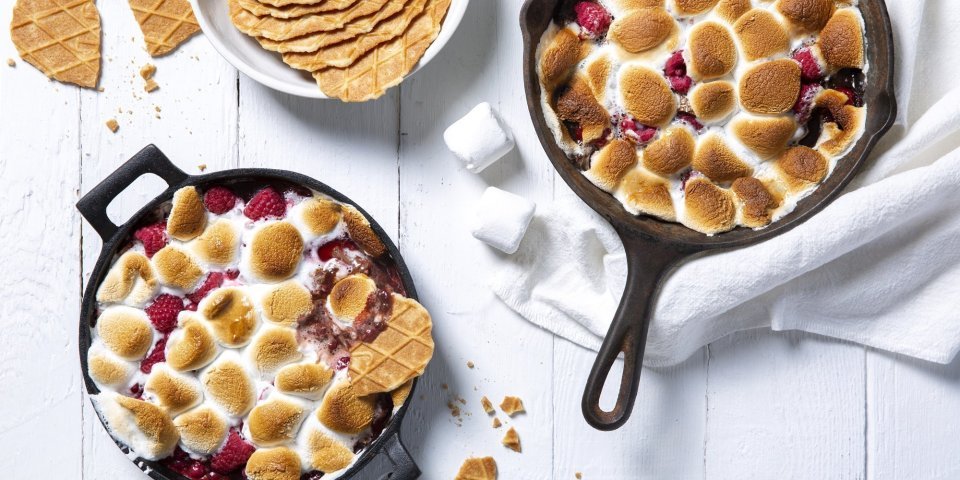 S’mores dip met frambozen en rode besjes S'mores dip maak je met marshmallows die lichtjes in de oven gaan om te smelten en te kleuren. Wij voegden ook nog framboosjes en rode besje toe in onze gietijzeren zwarte pan. Een heerlijk dessert om te dippen met Jules Destrooper koekjes.