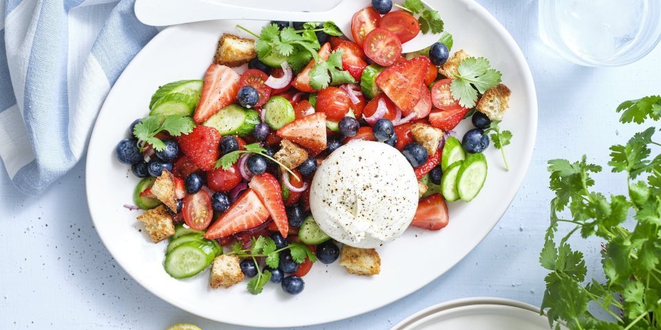 Salade met kerstomaten, aardbei en burrata Er staat een grote schaal op tafel boordevol zomerse toppers. Denk maar aan tomaatjes, aardbeien, bosbessen, komkommers en burrata. Dit geeft echt verfrissing tijdens een zwoele zomerdag. Er ligt een citroentje langs, een glas water en verse kroiander.