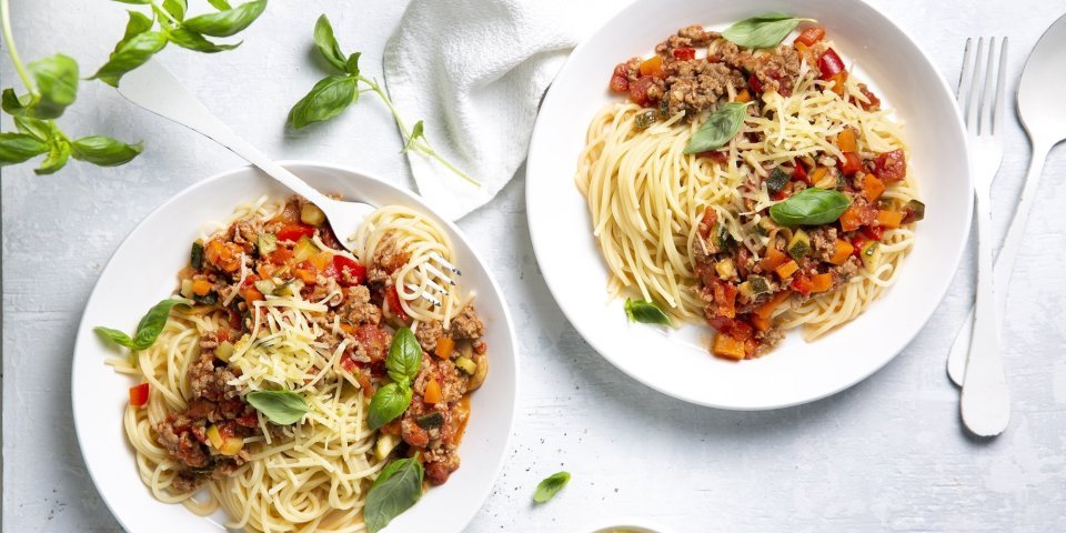 Twee borden gevuld met huisgemaakte spaghetti bolognaise. Afgewerkt met basilicumblaadjes die zorgen voor extra smaak en kleur in je bord. 