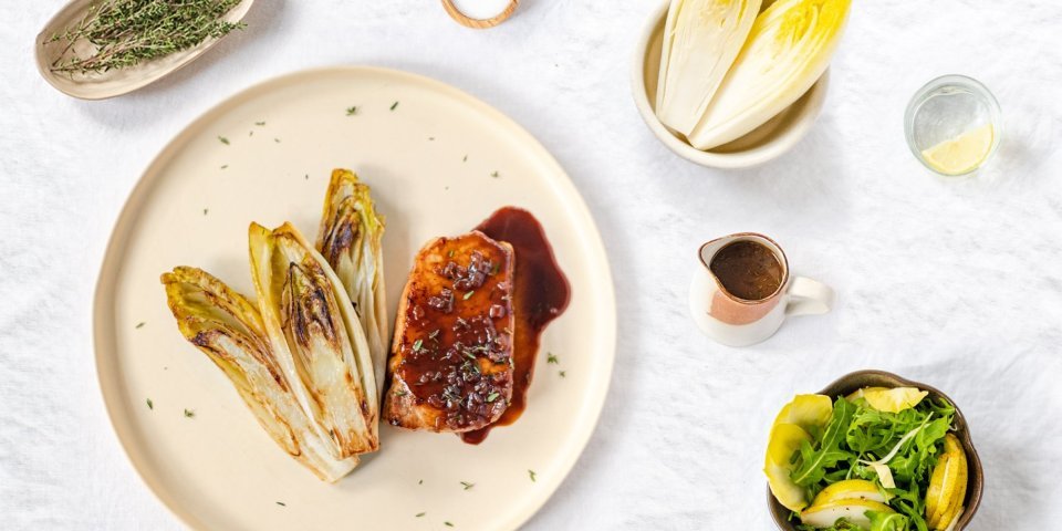 Varkensmignonette met witloof en Luikse saus Gestoofd witloof ligt naast een heerlijk stukje varkensvlees gepresenteerd. De luikse saus kleurt heerlijk zoetbruin.