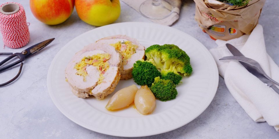 Varkensrollade met een vulling van appel en spek De varkensrollade ligt aangesneden op een bord. Twee ronde schijfjes met in het midden de vulling van appel en spek. We serveren deze varkensrollade met broccoli en de sjalotjes.