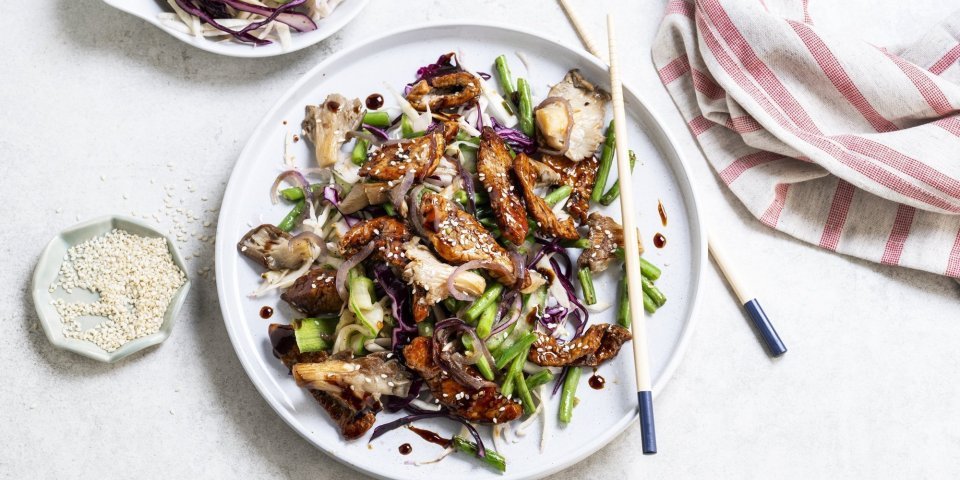 Wok van kalfsvlees, boontjes, kolen en oesterzwammen Op tafel staat een groot wit bord met hierop het gerechtje uitgeschept. Het vlees kreeg een mooi sticky kleurtje door de marinade. De boost aan groentjes is aanwezig in dit gerechtje.