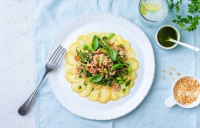 Fijn gesneden aardappel schijfjes met groene sla en verse garnalen.