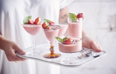 Roze bavarois geserveerd in verschillende glaasjes op een dienplateau. Een vrouw met witte t-shirt draagt deze roze dessertjes, klaar om naar de gasten te brengen.